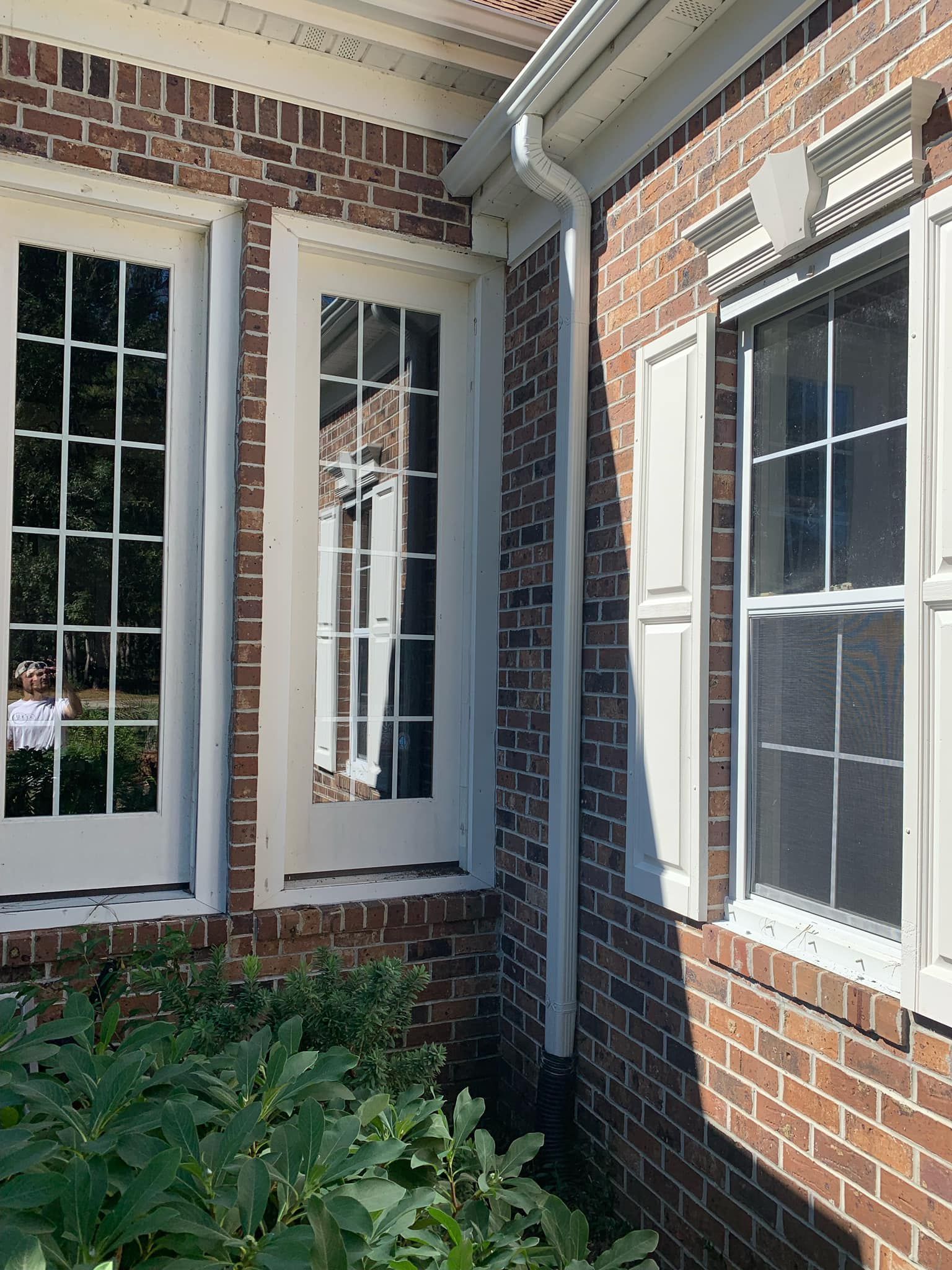 A brick building with white shutters and a blue sky in the background.