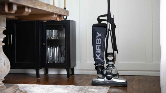 A kirby vacuum cleaner is sitting on the floor in a living room.