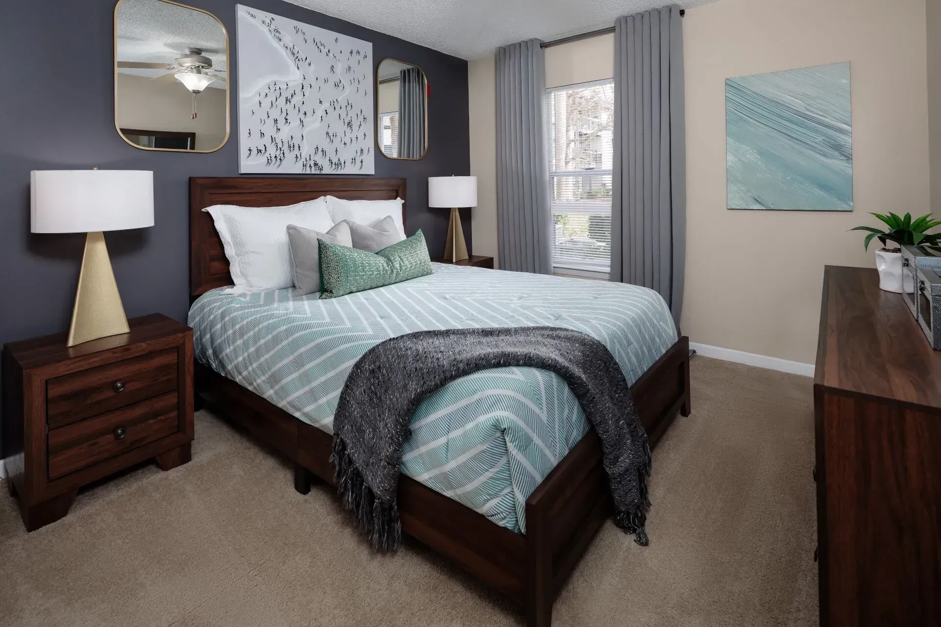 Bedroom with a dark wood bed, nightstands, and dresser; gray and teal accents, beige carpet.