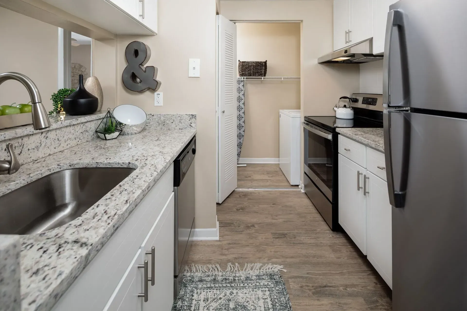 Kitchen with granite countertops, white cabinets, stainless steel appliances, and a laundry room.