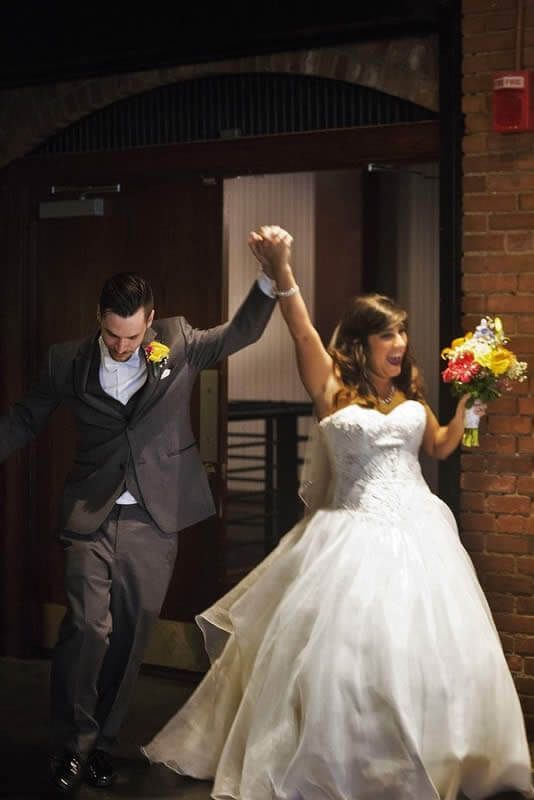 A bride and groom are holding hands while walking through a doorway.
