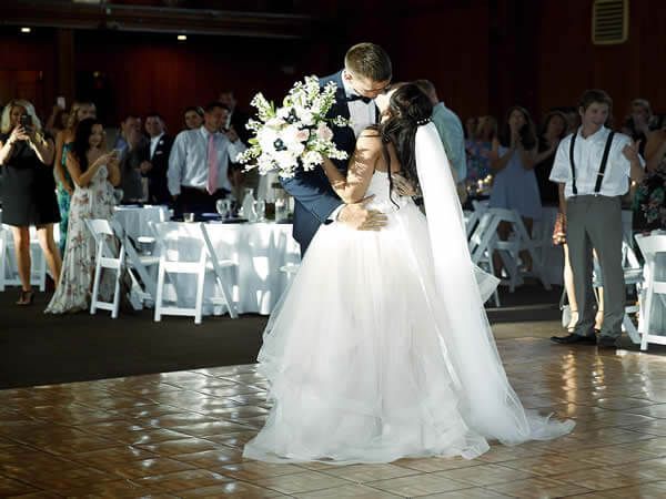 A bride and groom are kissing on a dance floor at their wedding reception.