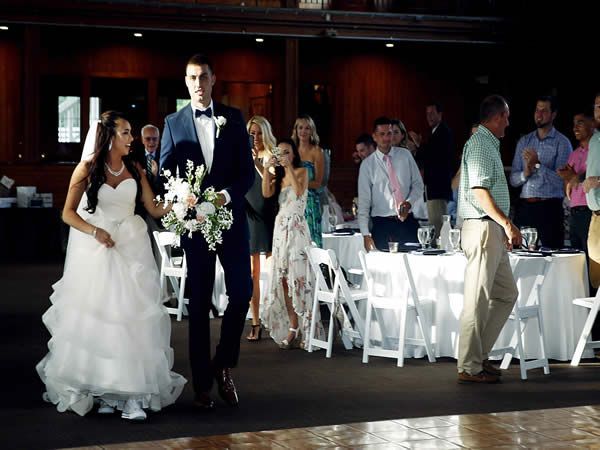 A bride and groom are walking down the aisle at their wedding reception