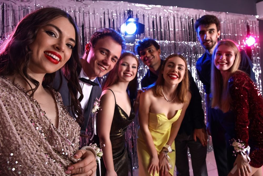 A group of young people are posing for a picture at a prom.