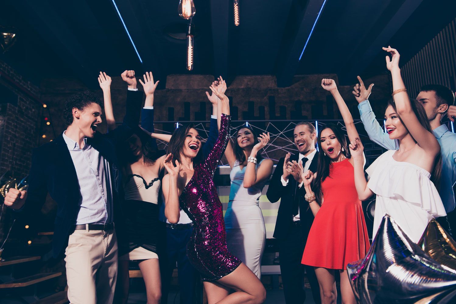 A group of people are dancing at a party in a club.