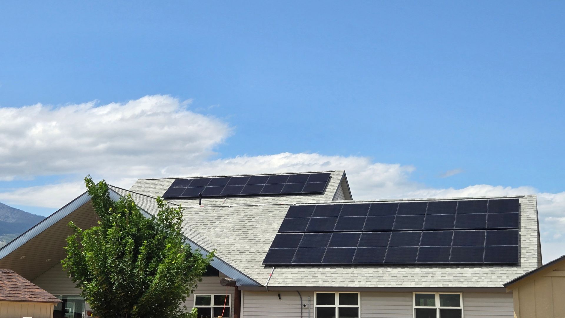 Solar panels on a residential roof against a blue sky with clouds.