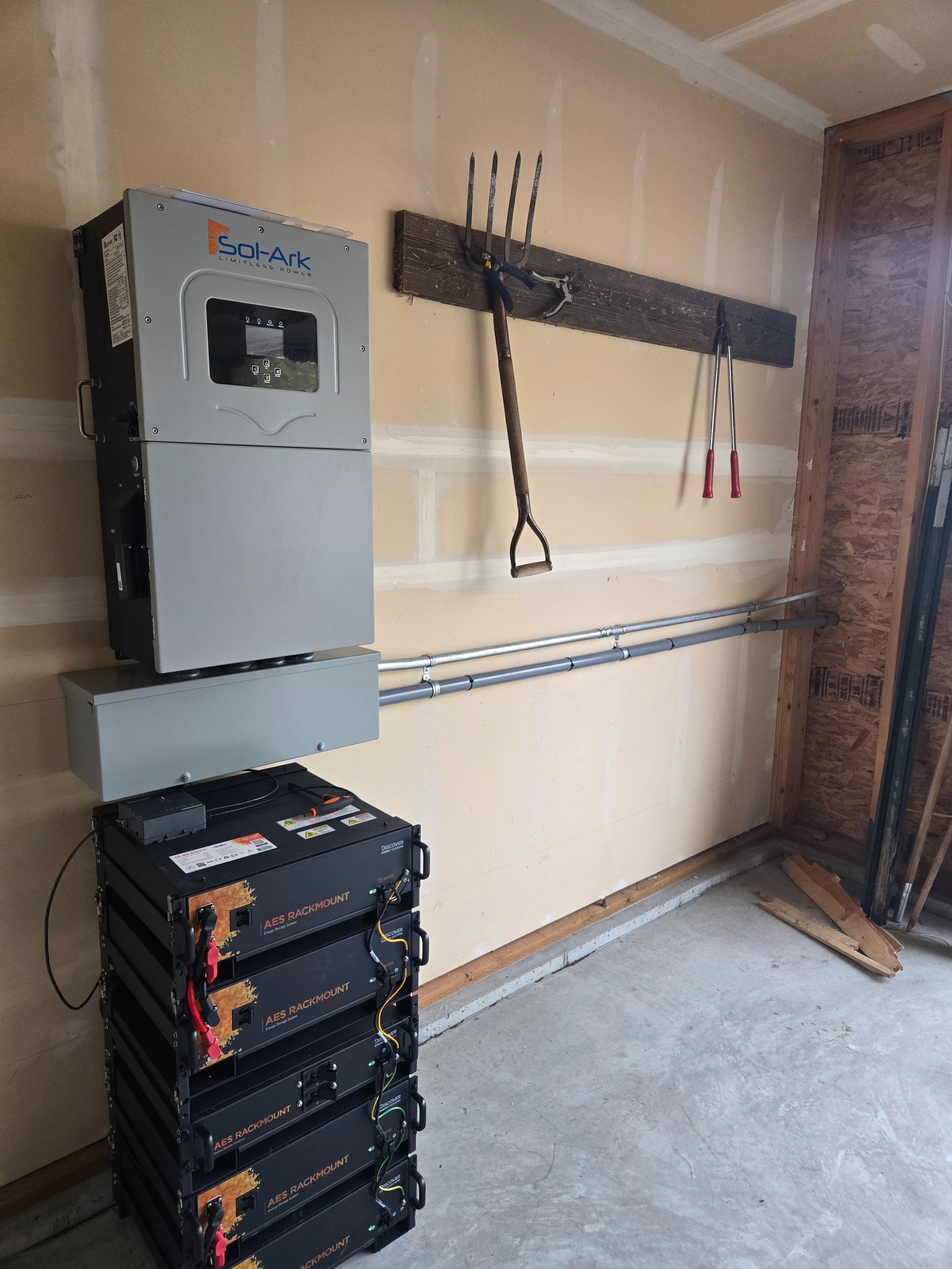 Solar power inverter and battery system installed on a garage wall, gray and black components.
