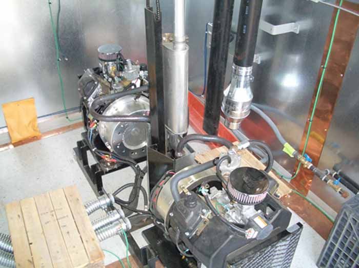 Two gasoline engines mounted on black bases inside a metal enclosure.