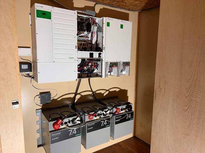 Solar power system with batteries and inverter mounted on a wall in a room.