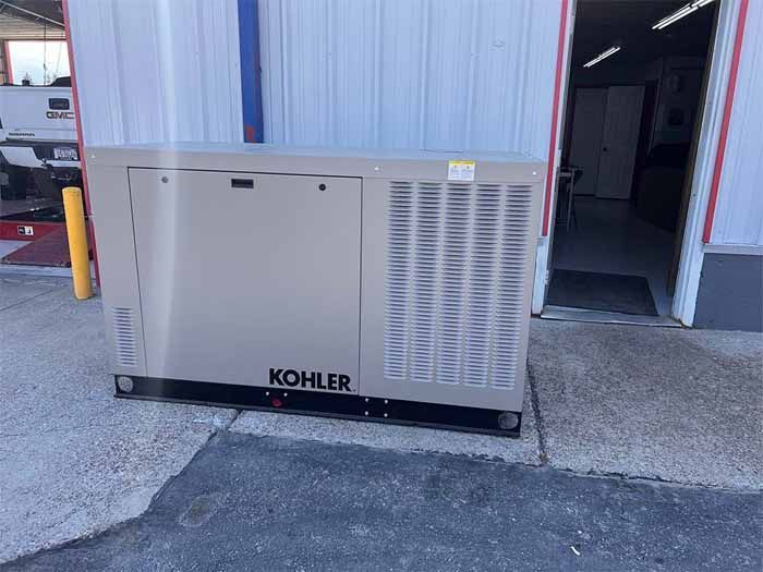 A Kohler generator outside a building with the door open.