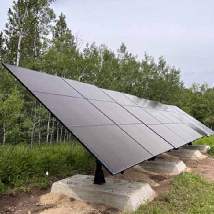 Solar panels on concrete bases in a grassy field, with trees in the background.