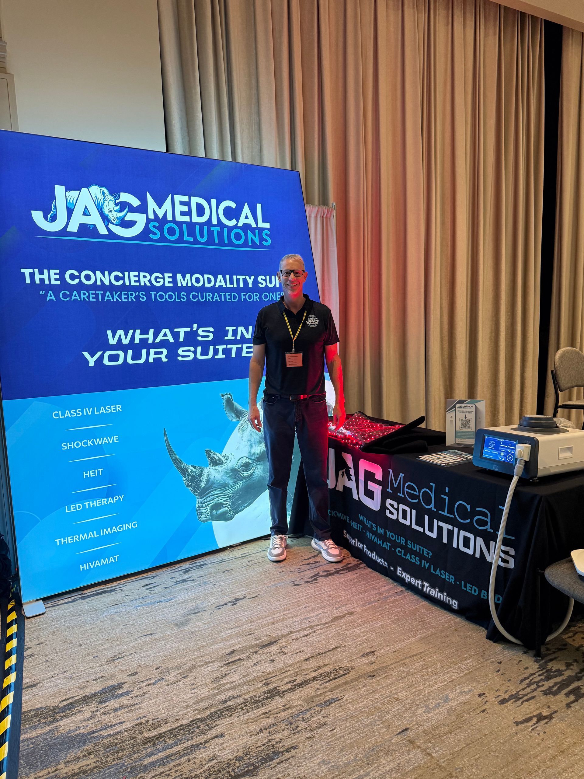 Man stands at a medical solutions booth with a rhino graphic and a table with medical equipment.