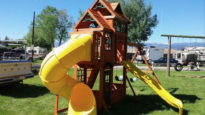 A wooden playground with a yellow slide and swings.