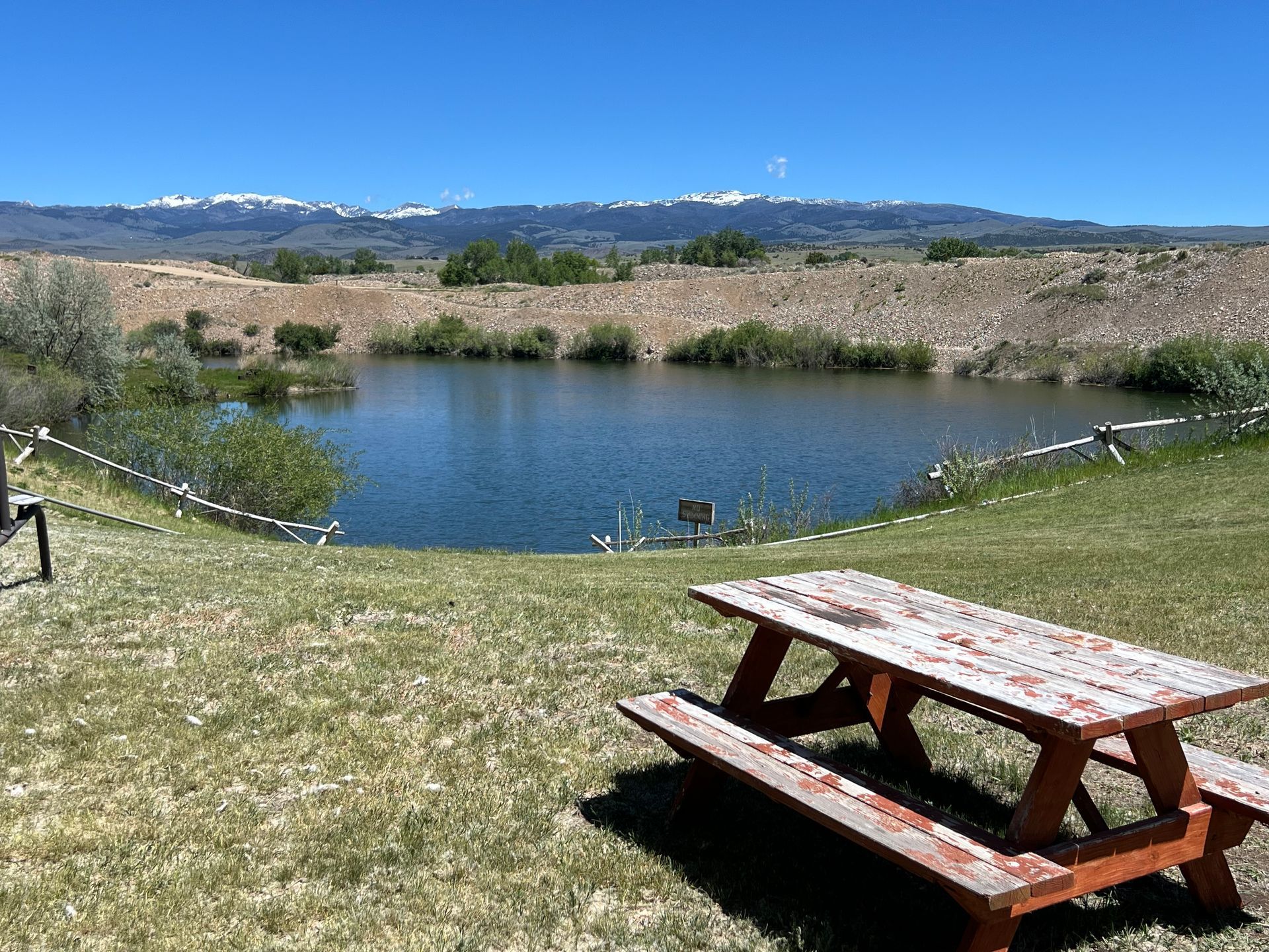 A picnic table in front of a lake with mountains in the background