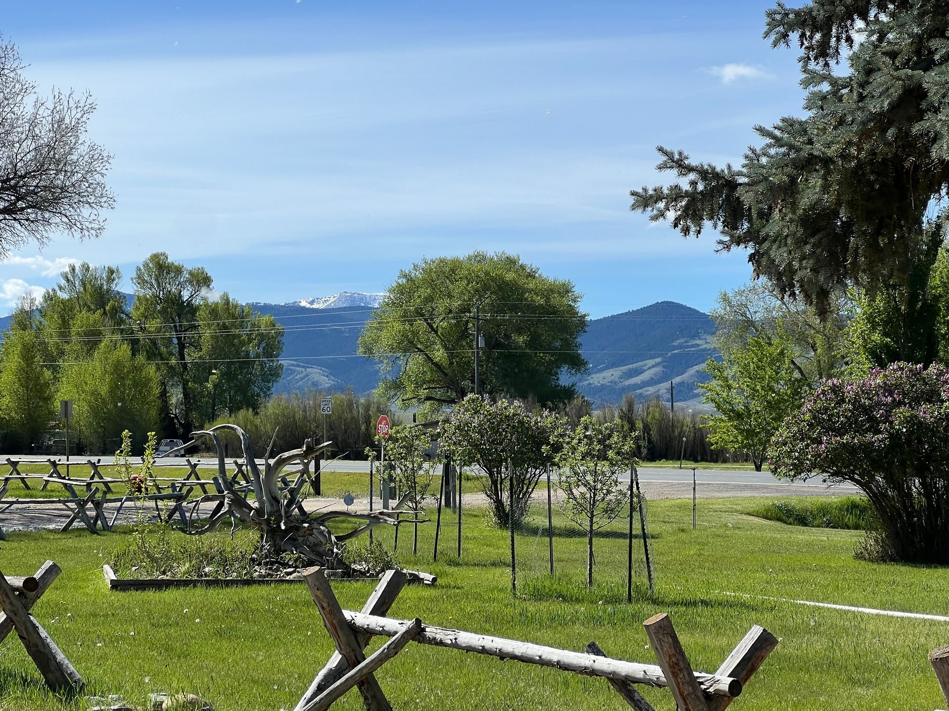 A wooden fence in a grassy field with mountains in the background