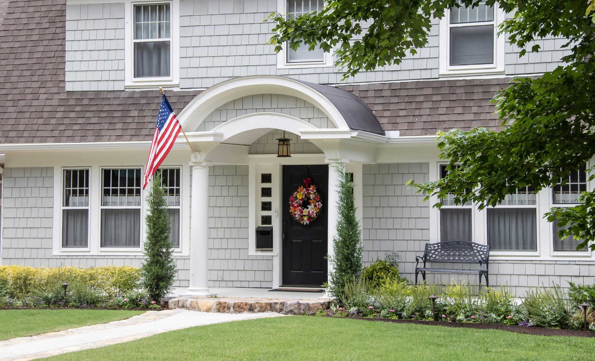 White house with American flag, wreath on the door, green lawn.