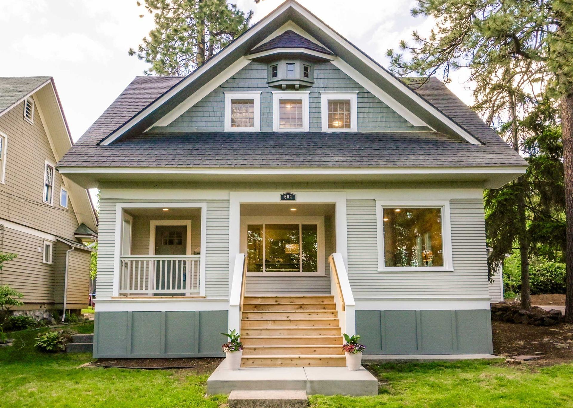 Cozy Craftsman home with green and grey siding, wooden steps, and a small front porch.