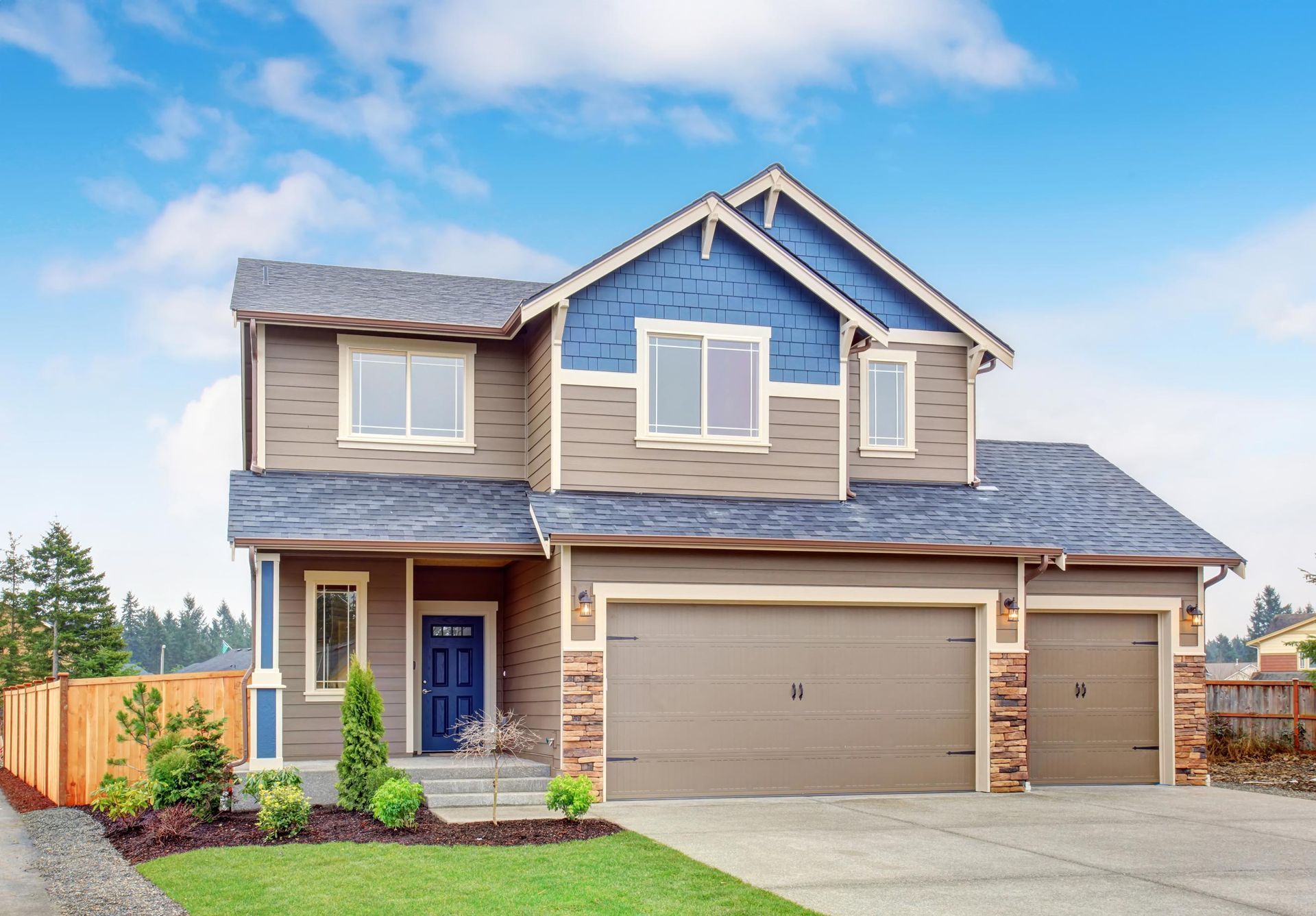 Two-story house with brown and blue siding, blue door, and three-car garage on a sunny day.