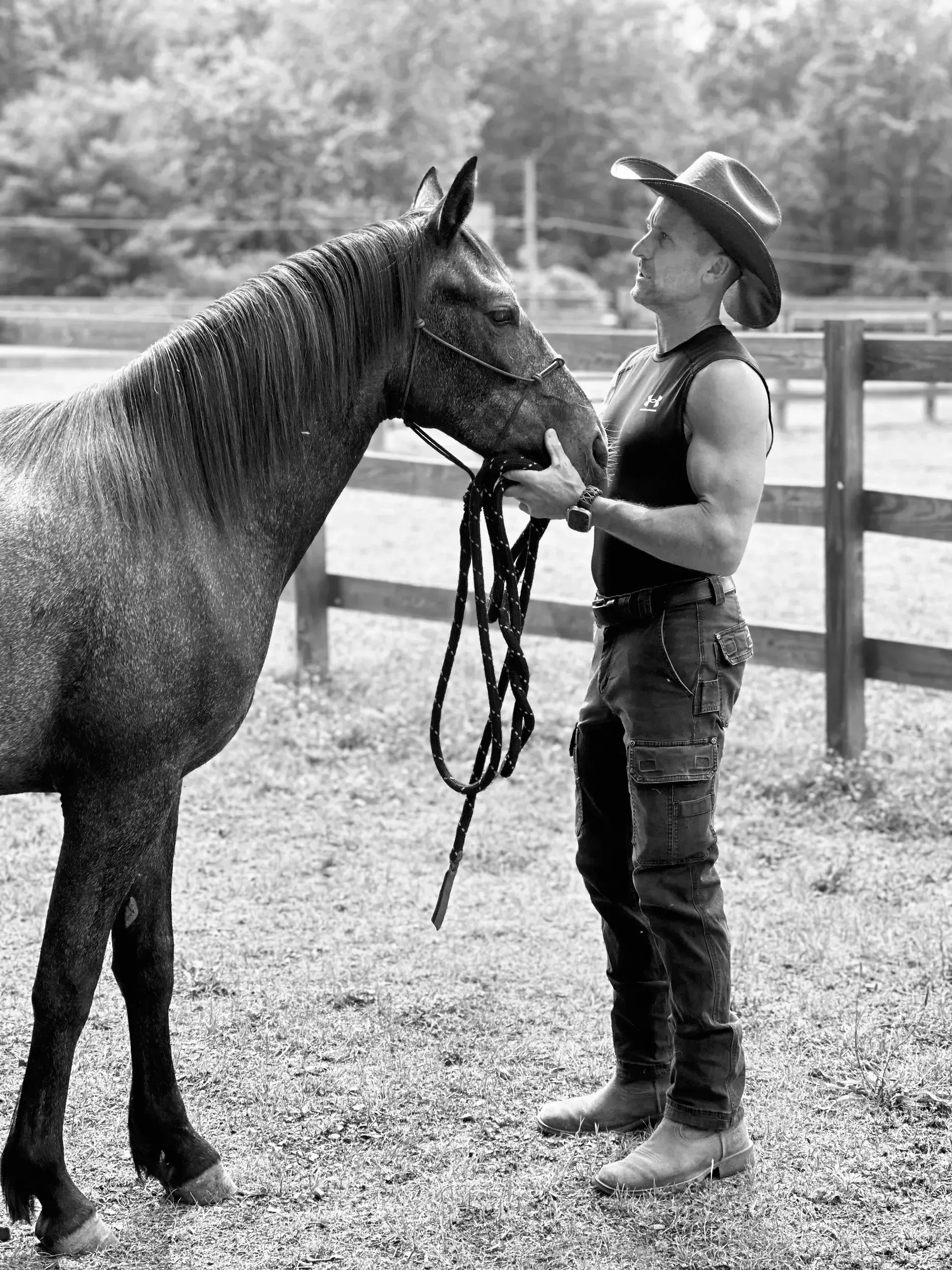 A man in a cowboy hat is standing next to a horse.