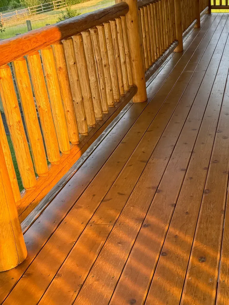 Wooden deck with log railing, bathed in warm sunlight.