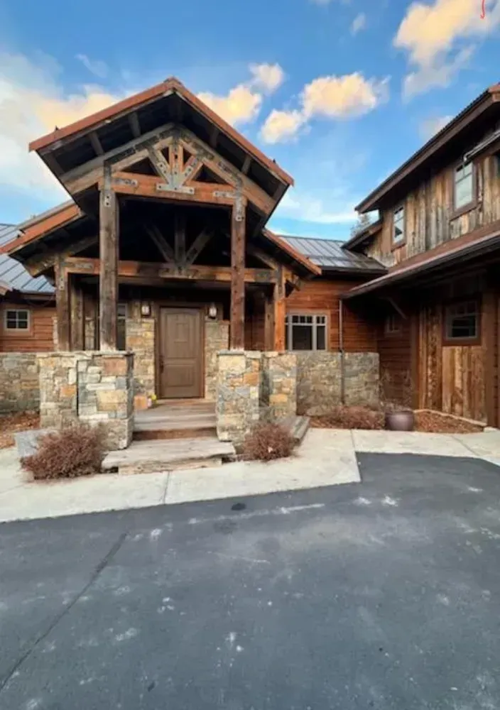 Rustic wooden home with stone accents and a covered entryway.