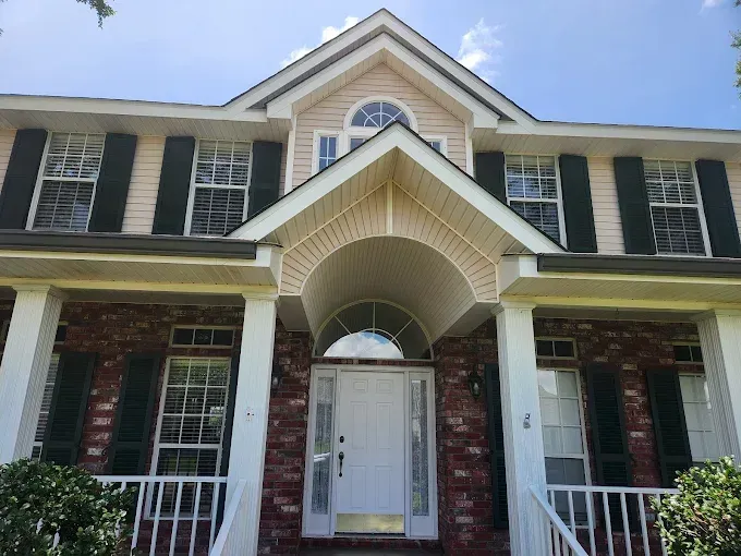 Two-story house with red brick and beige siding, white trim, and a covered front porch.