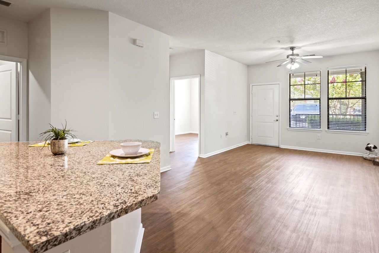 Open-concept living area with granite kitchen island, wood floors, and large windows.