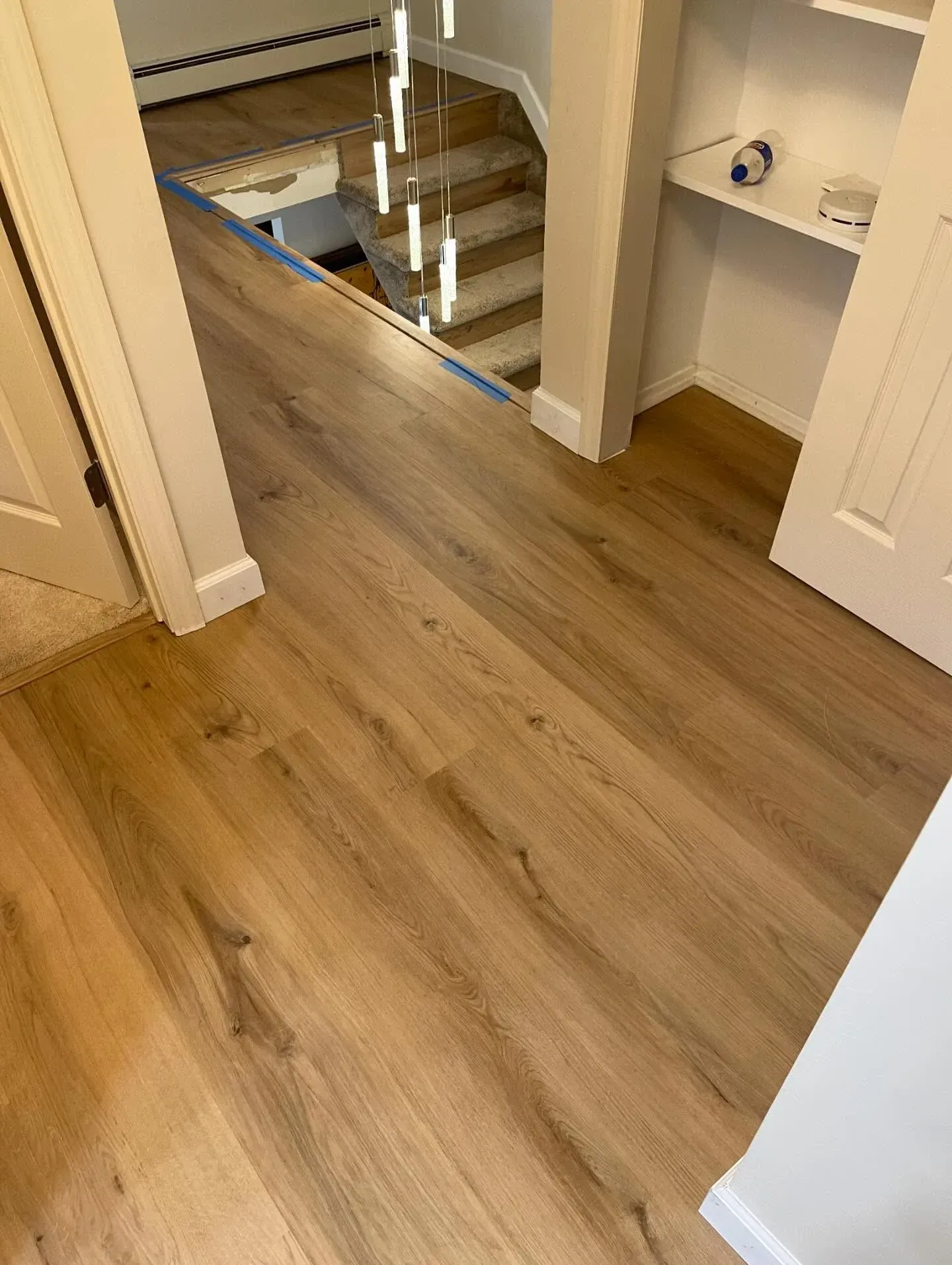Interior hallway with wood flooring, open stairwell, and built-in shelves.