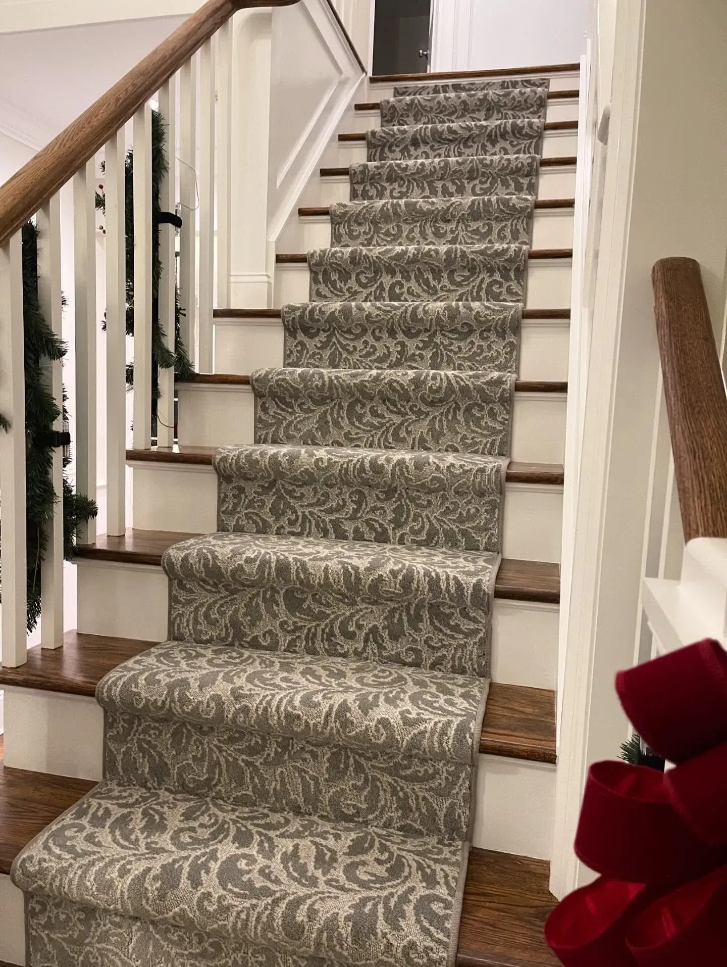 Carpeted staircase with patterned runner and wooden banisters in a home interior.