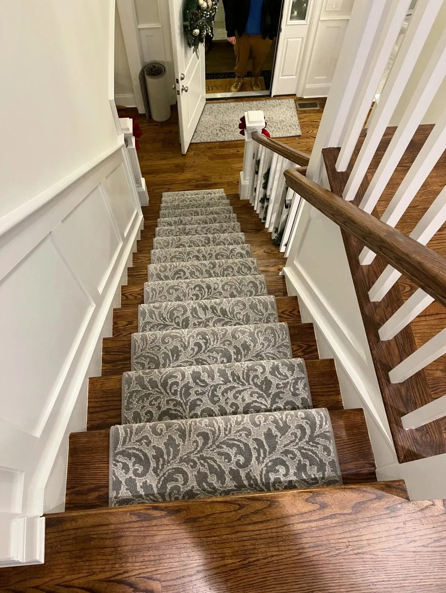 Staircase with gray patterned runner, wooden banister, and hallway landing at the bottom