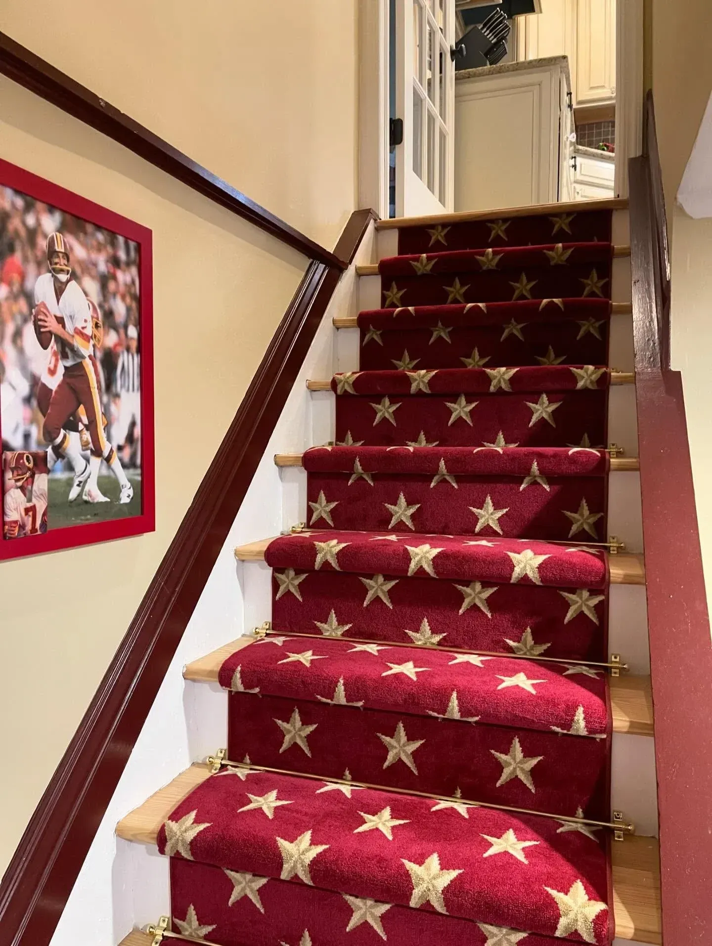 Carpeted staircase with red star-patterned runner and framed sports photo on the wall