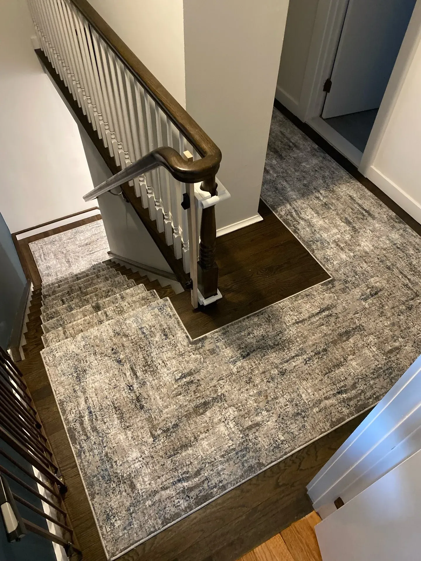Stair landing with carpet, white railing, and a doorway in a home hallway.