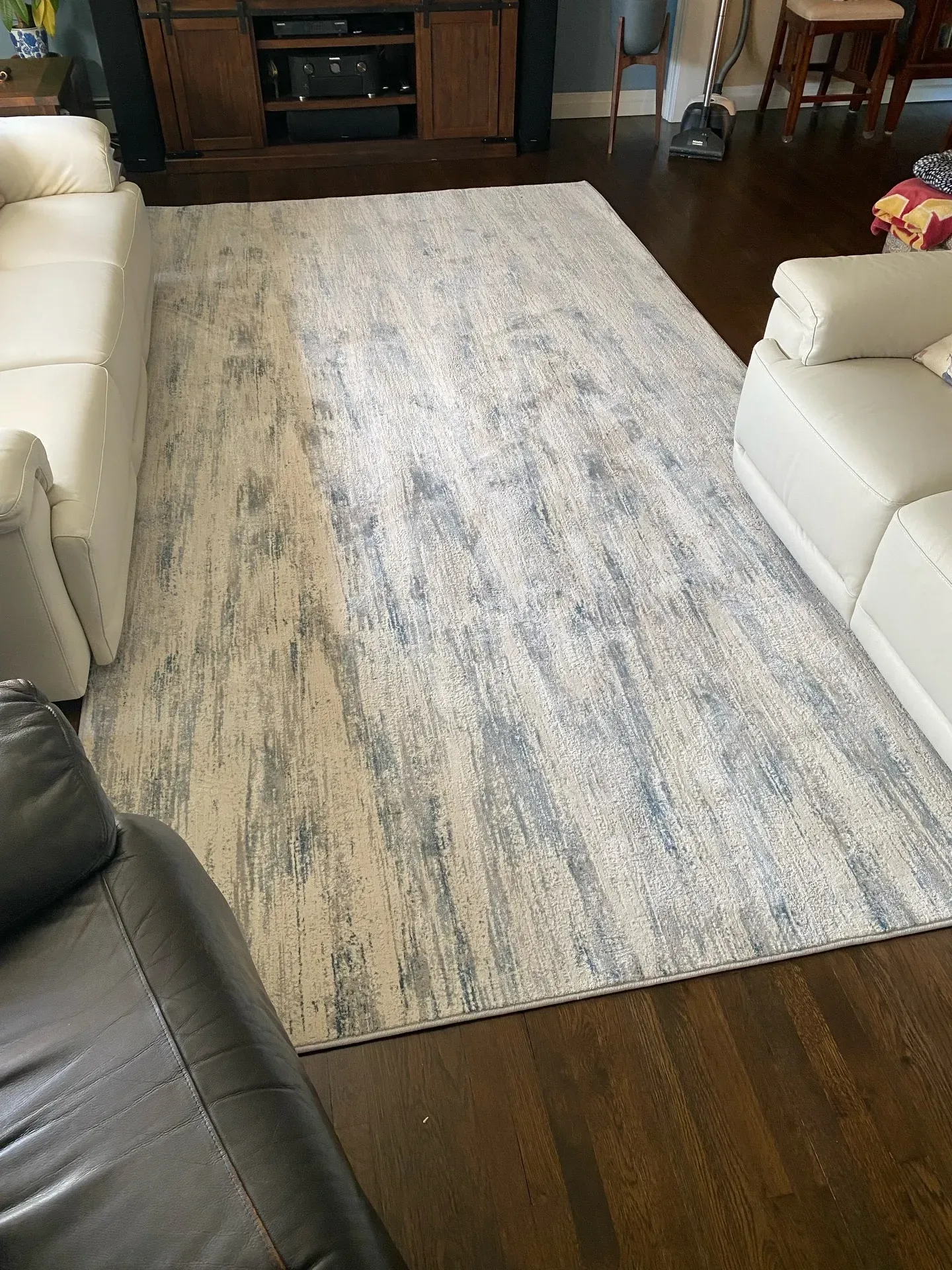 Living room with a light blue and cream area rug between white sofas and a dark armchair
