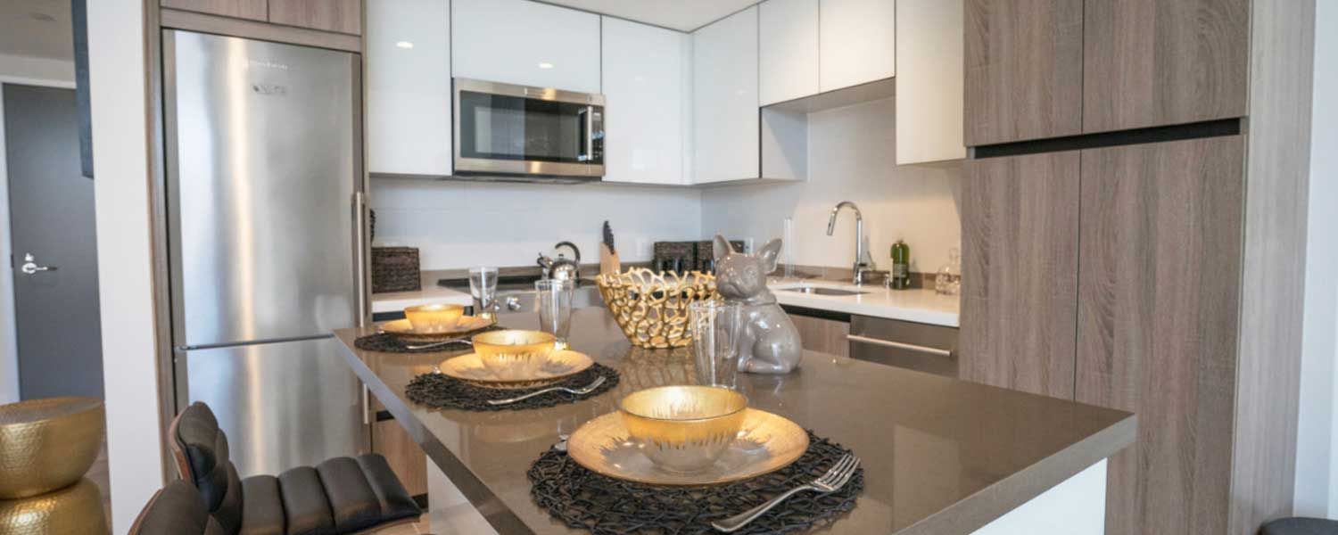 Modern kitchen with stainless steel appliances, white cabinets, and a gray island with place settings.