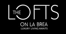 Logo for The Lofts on La Brea, white text on black background. "The Lofts" above "On La Brea" and "Luxury Living Awaits".