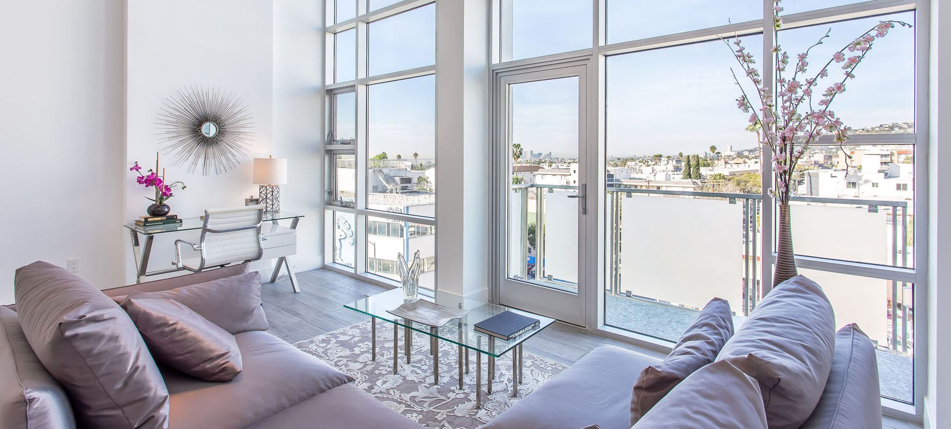 Modern living room with large windows, city view, and a gray sofa.