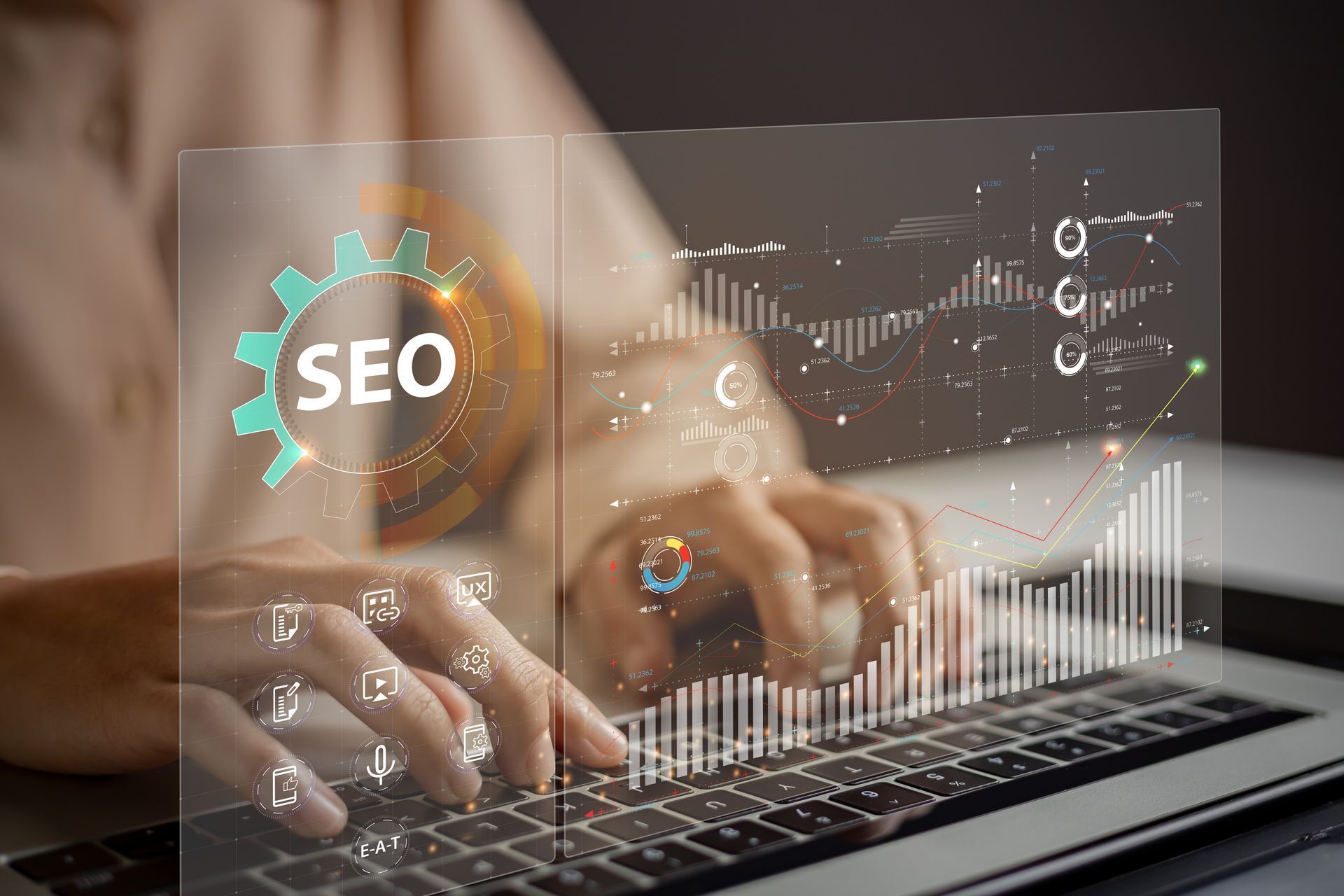 A person is typing on a laptop computer with a screen behind them that says seo.