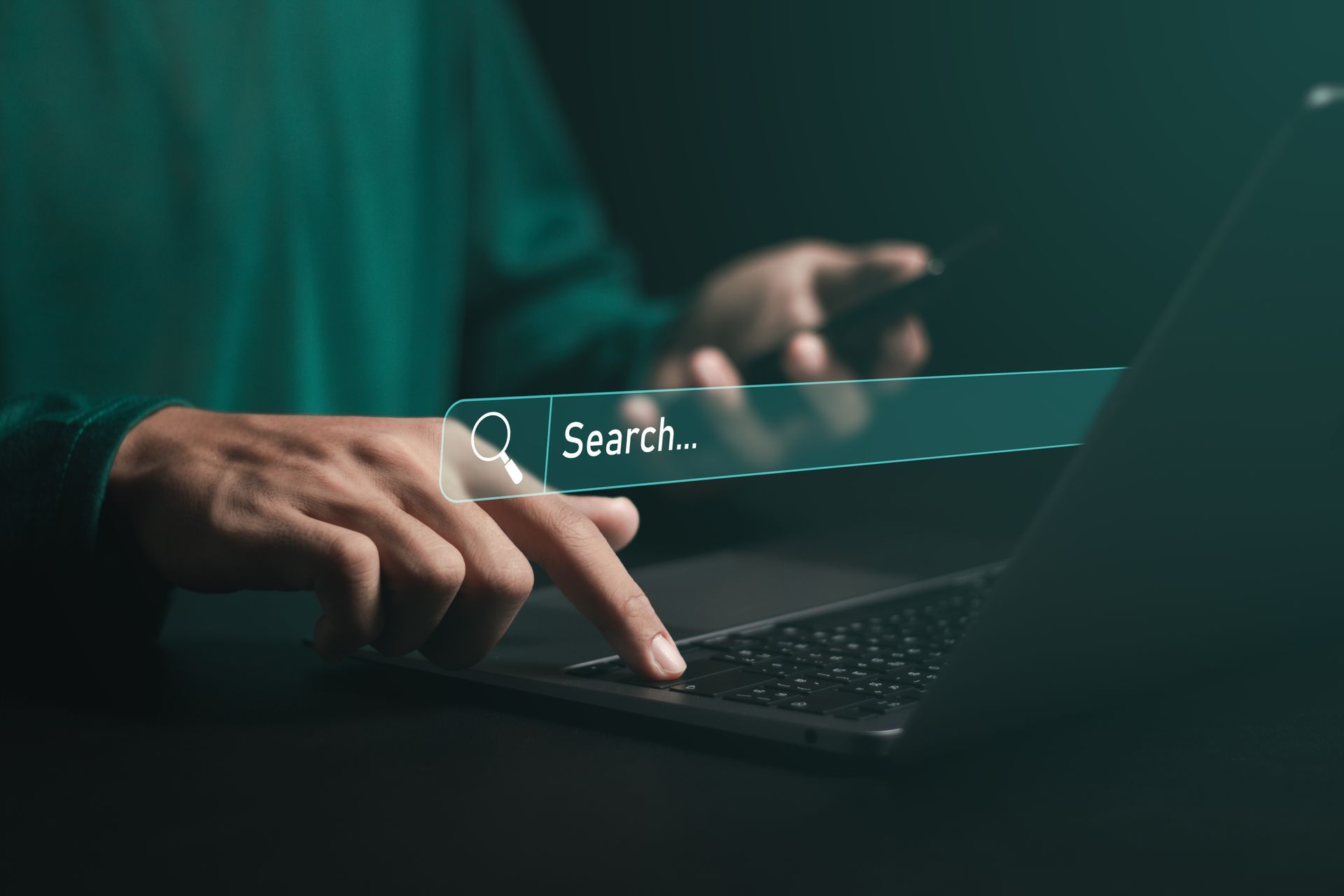 A person is using a laptop computer with a search bar on the screen.