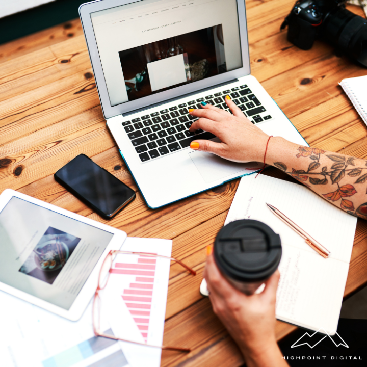 A woman is typing on a laptop while holding a cup of coffee
