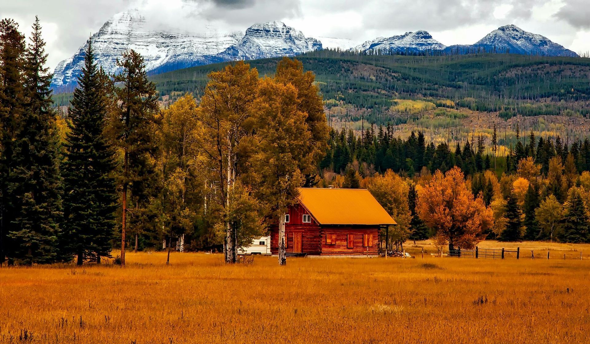 A cabin in the middle of a field with mountains in the background.
