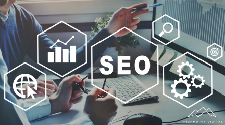 A group of people are sitting at a table looking at a laptop computer.