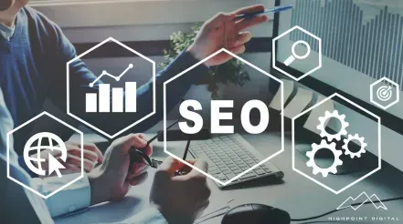 A group of people are sitting at a table looking at a laptop computer.