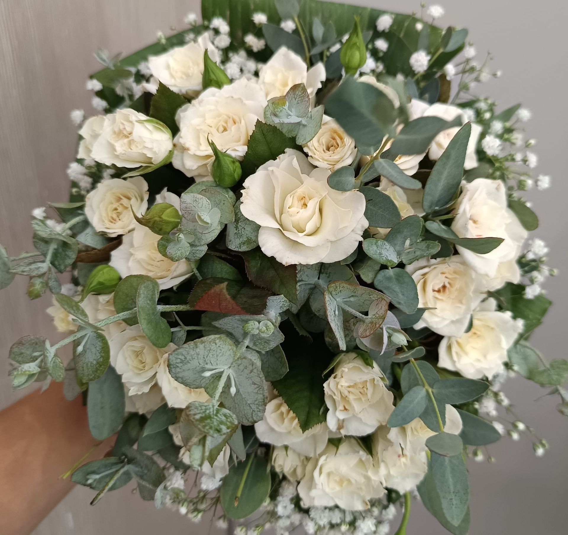 Una persona tiene in mano un mazzo di rose bianche e gypsophila