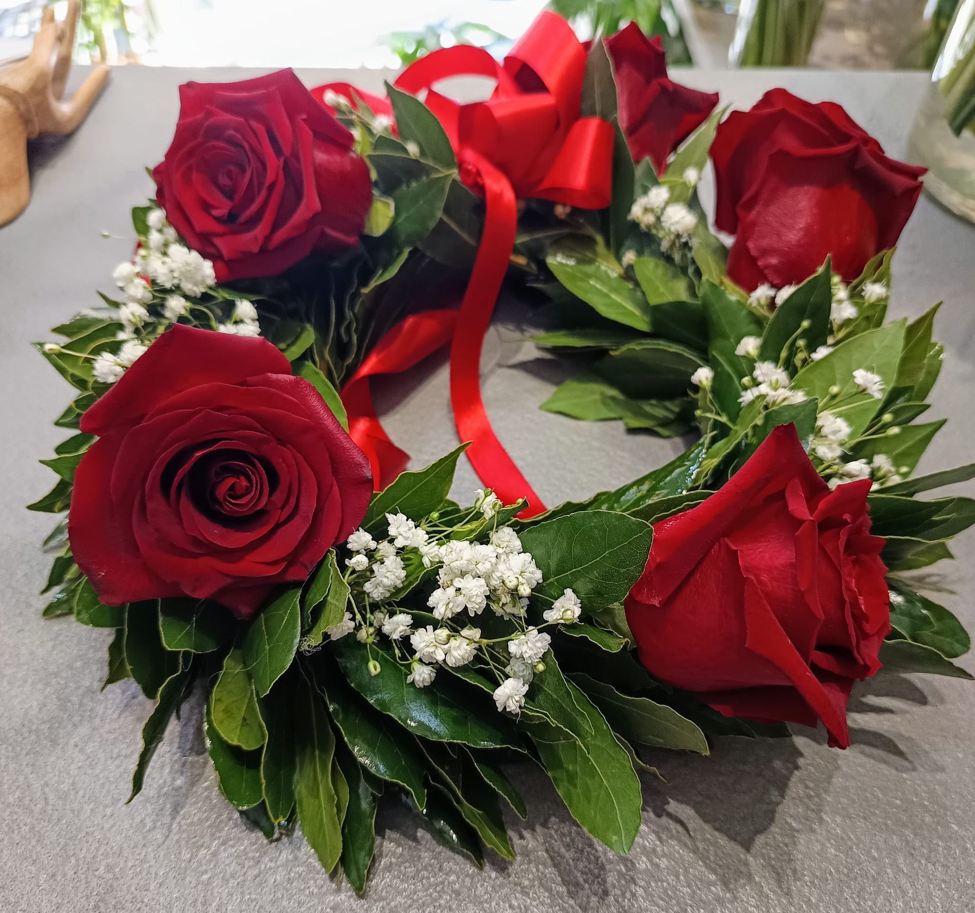 Una corona con rose rosse e gypsophila bianca