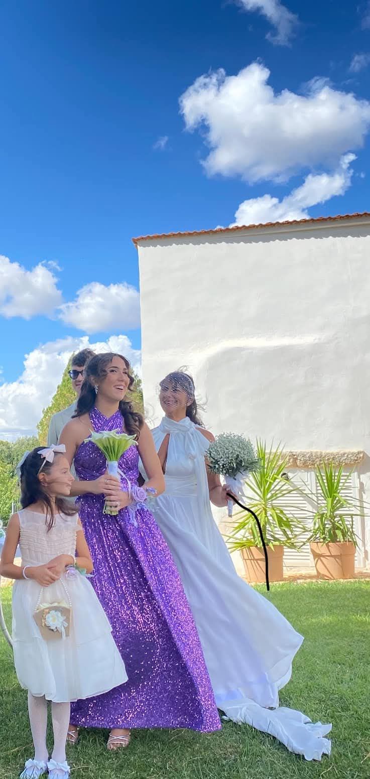 Una donna con un vestito viola è in piedi accanto a due damigelle.