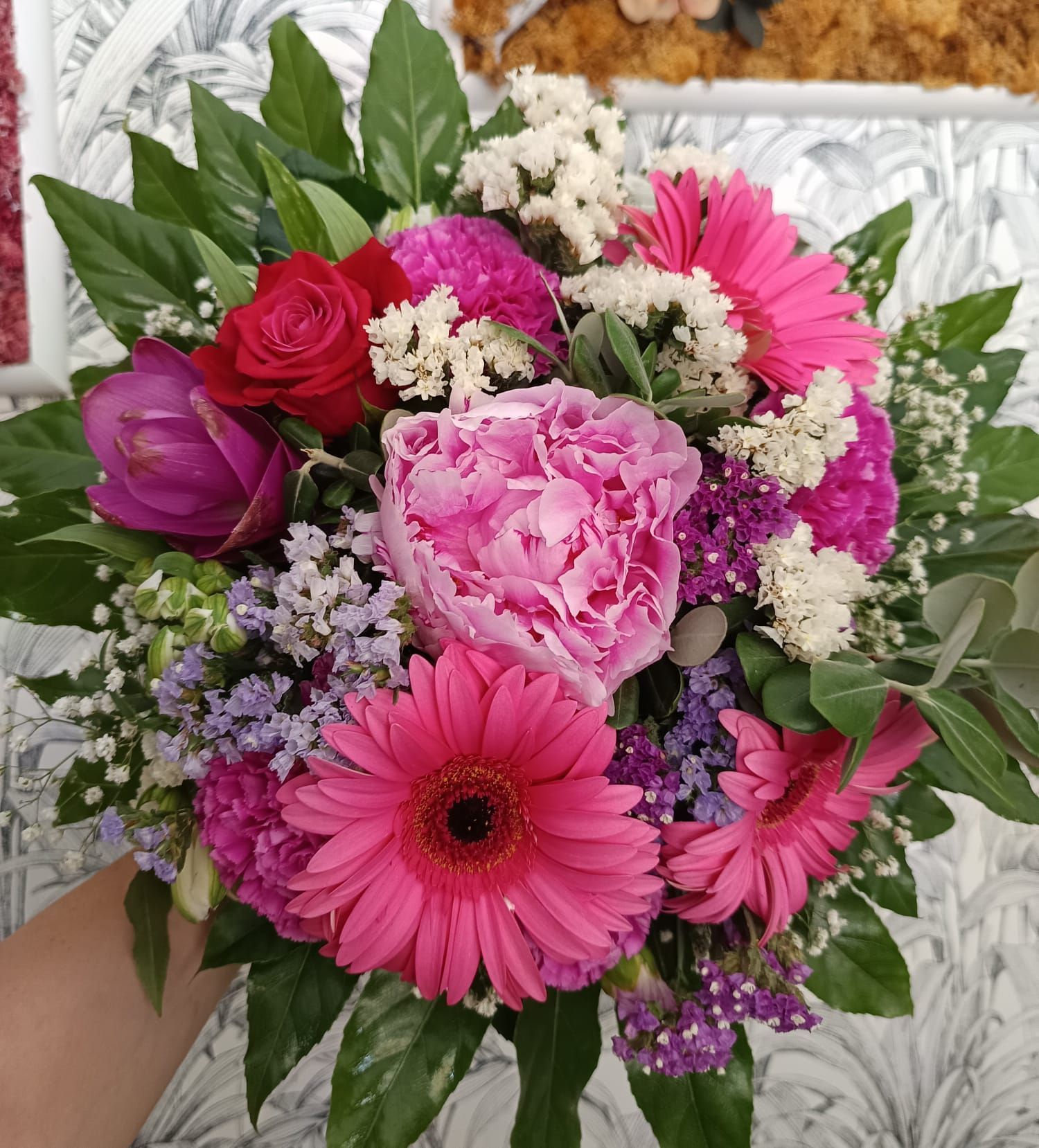 Una persona tiene in mano un mazzo di fiori rosa e viola