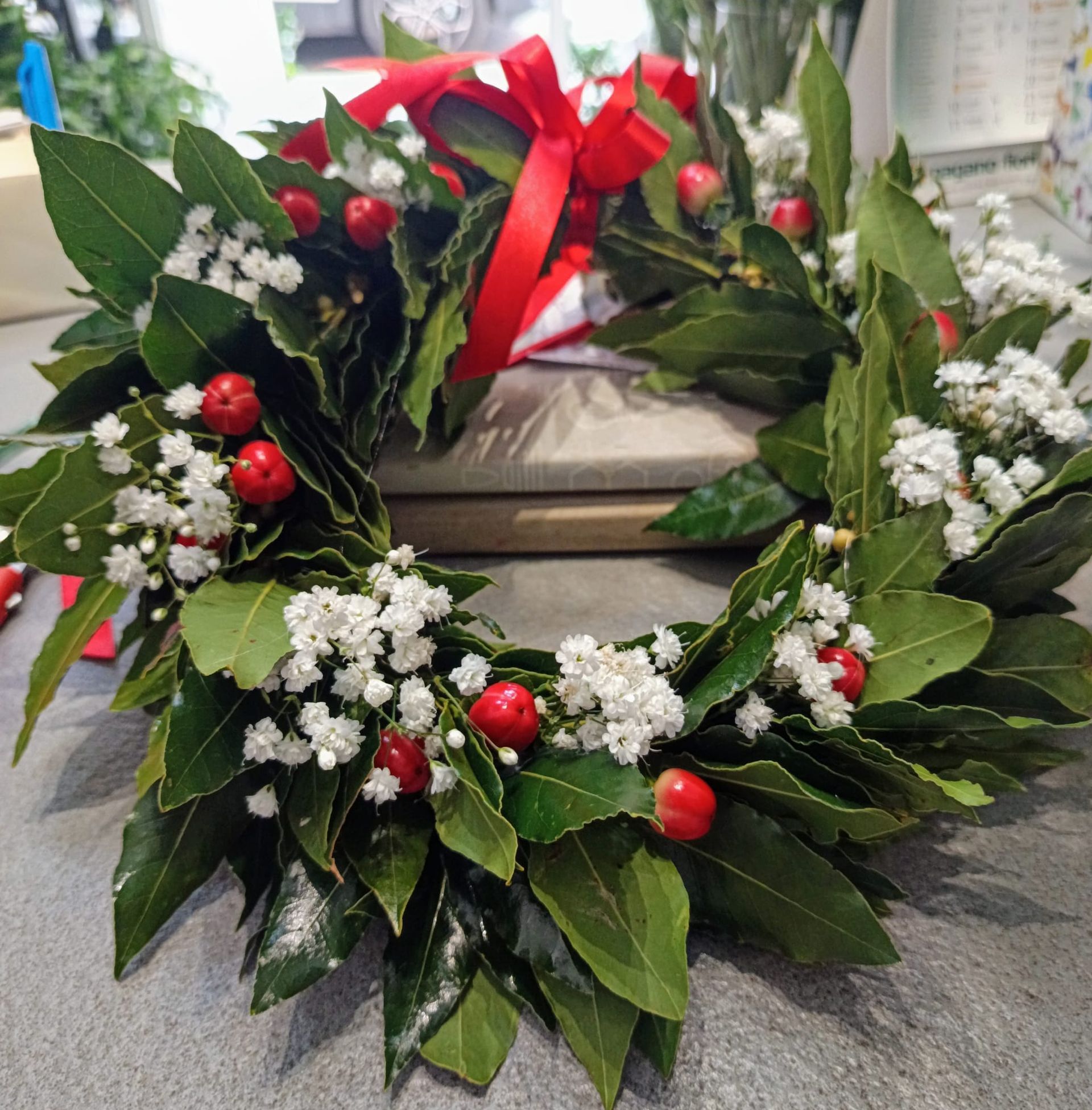 Una corona con bacche rosse e fiori bianchi su un tavolo