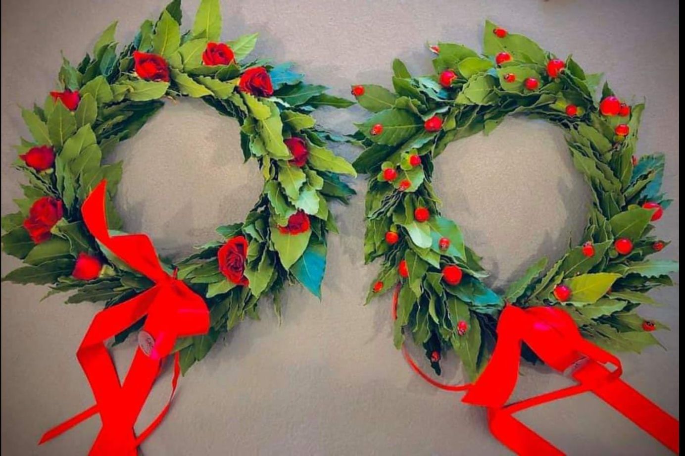 Due corone verdi con fiori rossi e nastri rossi