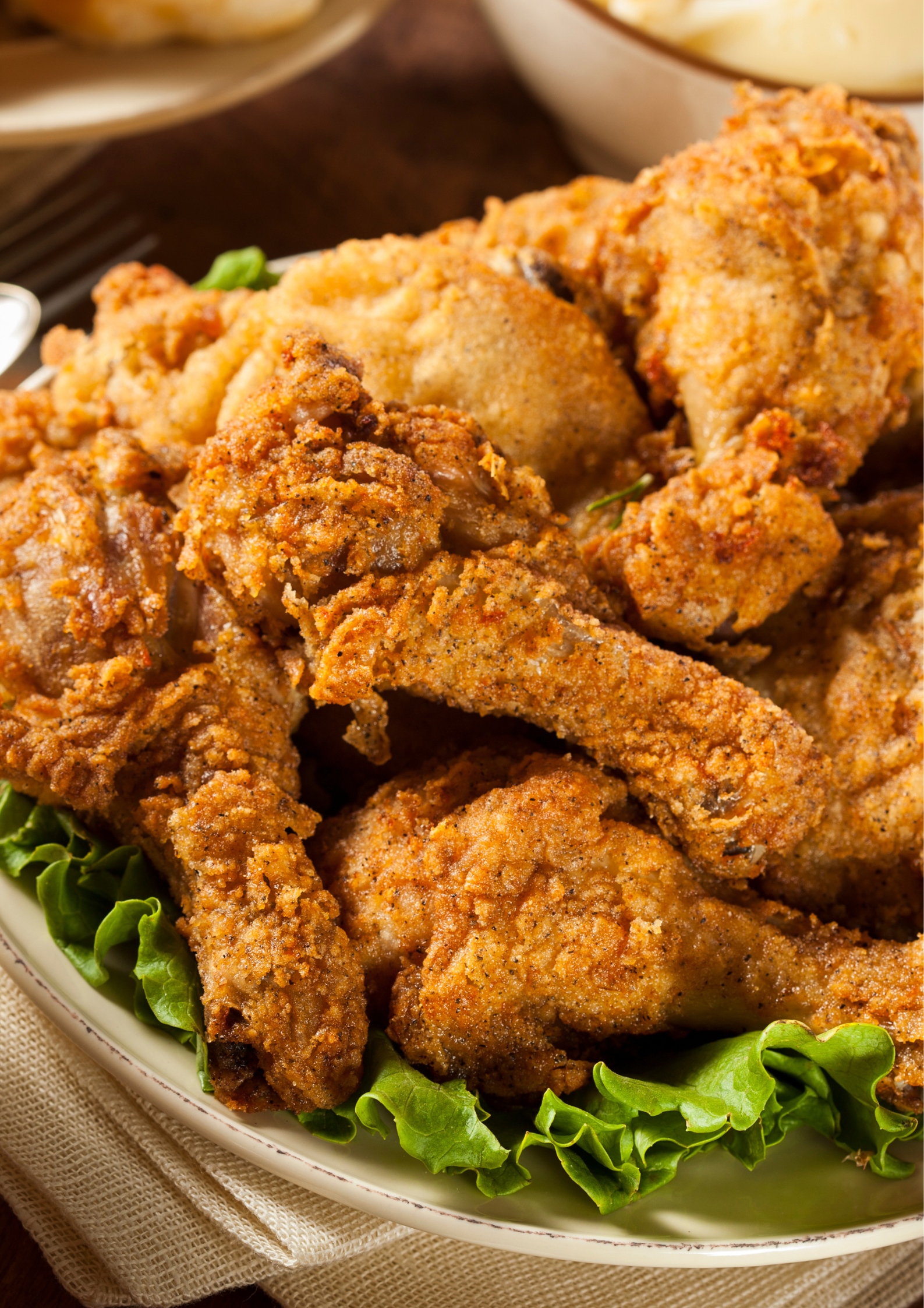 A white bowl filled with fried chicken and lettuce on a table.