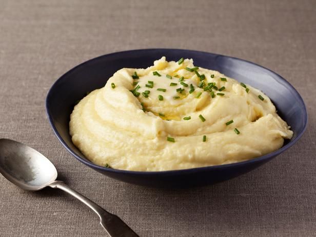 A bowl of mashed potatoes next to a spoon